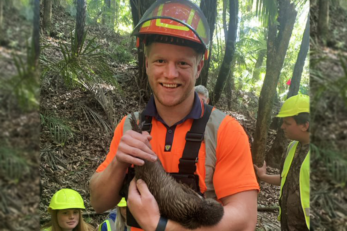 Seamus holds a kiwi in the forest